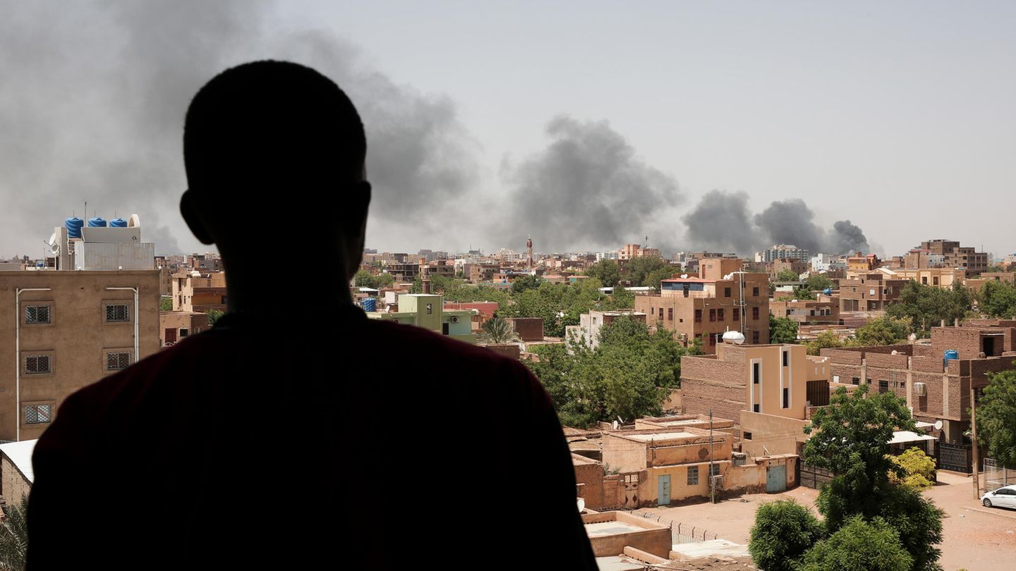 Мужчина смотрит на столб дыма в охваченном боем Хартуме.