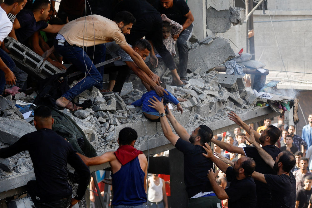 Рятувальники витягують дитину з-під уламків будівлі, яка постраждала внаслідок авіаудару Ізраїлю в Хан-Юнісі на півдні сектора Газа у вівторок. Фотографія: AFP/Getty Images